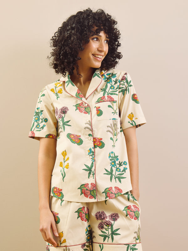 Woman wearing a floral pyjama set against a beige background