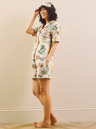 Woman wearing a floral pyjama set in a room with a beige wall and wooden floor.