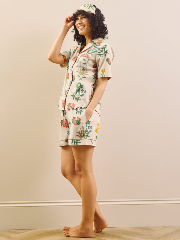 Woman wearing a floral pyjama set in a room with a beige wall and wooden floor.