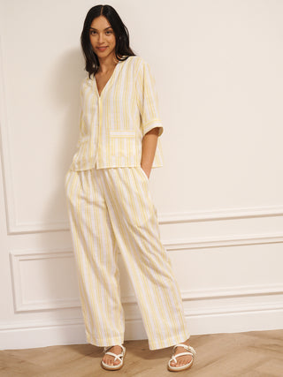 Woman wearing a yellow and white striped linen blend co-ord set with V-neck top and loose trousers. Front view