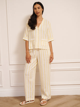 Woman wearing a yellow and white striped linen blend co-ord set with V-neck top and loose trousers.