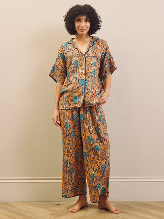 Woman wearing a patterned pyjama set against a plain background
