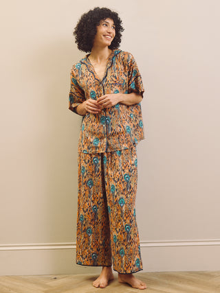 Woman wearing a patterned pyjama set against a plain background