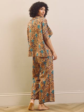 Woman wearing a patterned pyjama set against a beige wall.