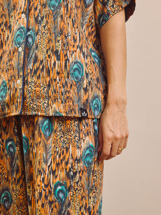 Person wearing a peacock feather pattern pyjama set on a beige background