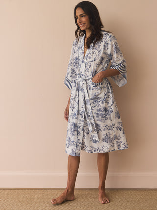 Woman wearing a floral patterned  dressing gown robe against a beige wall.