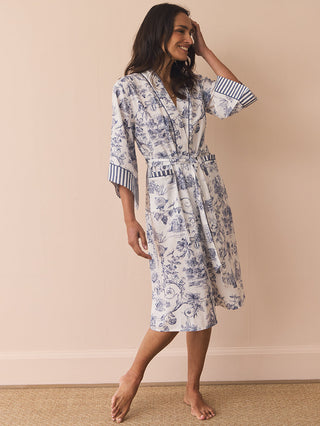 Woman wearing a floral patterned dressing gown robe against a beige wall.