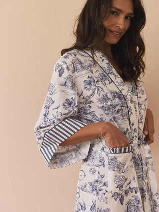 Woman wearing a white floral dressing gown with blue accents against a beige background