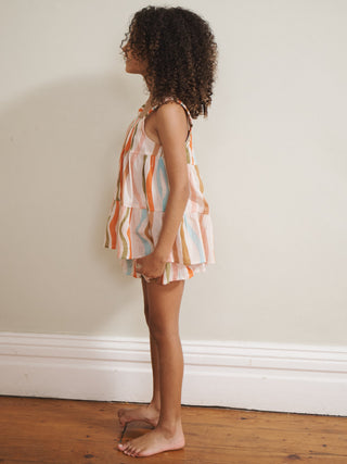 Girl wearing a striped dress pyjamas against a plain wall.