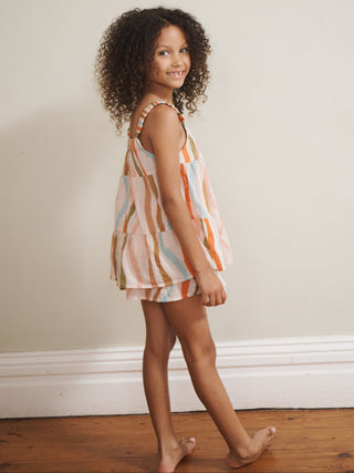 Young girl in a striped pyjamas standing against a plain wall.