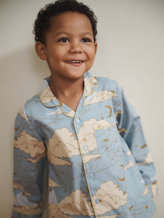 Child wearing a blue pyjama top with cloud pattern against a plain background