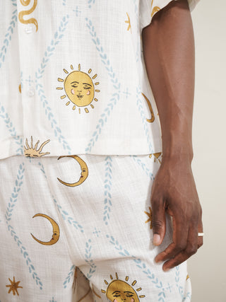 Person wearing a cream pyjama set with gold celestial patterns on a light background