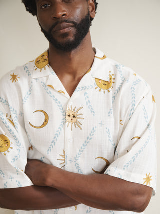 Man wearing a cream pyjama shirt with celestial pattern against a plain background
