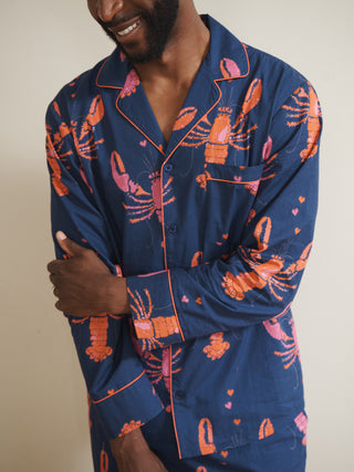 Person wearing navy blue pyjamas with Pink lobster pattern on a plain background