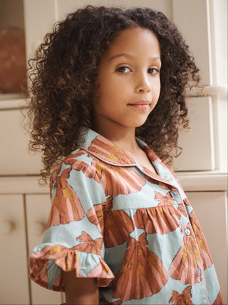 Young girl wearing a patterned pyjama set standing indoors.