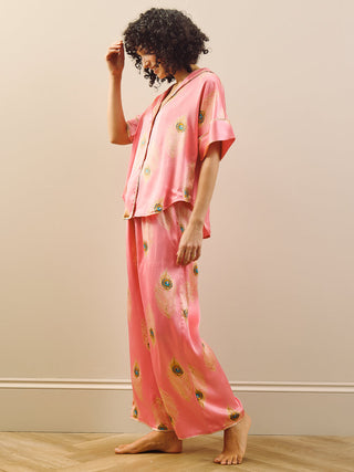 model wears pink long oversized pyjama set with peacock feather design. Side
