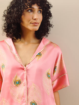 model wears pink long oversized pyjama set with peacock feather design. Detail close up