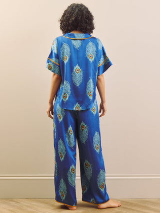 model wears blue long oversized pyjama set with peacock feather design. back