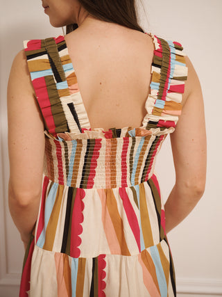Model wearing a multicolour striped cotton tiered dress with shirred bodice and wide ruffled straps, back detail. 