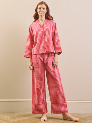 Model wears pinking gingham boxy pyjama set against a beige nurtural wall. 