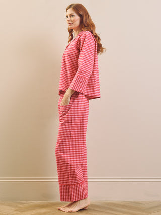 Model wears pinking gingham boxy pyjama set against a beige nurtural wall. 