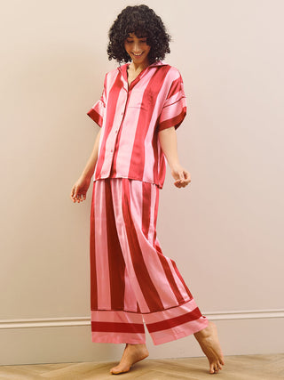 Model wearing a pink striped long pyjama set standing against a plain wall.