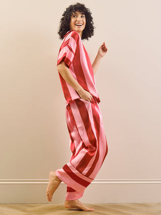 Model wearing a pink striped long pyjama set standing against a plain wall.