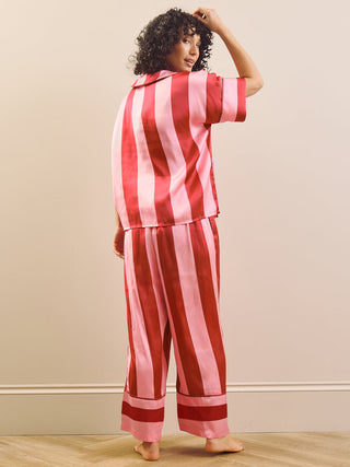 Model wearing a pink striped long pyjama set standing against a plain wall. Back Detail