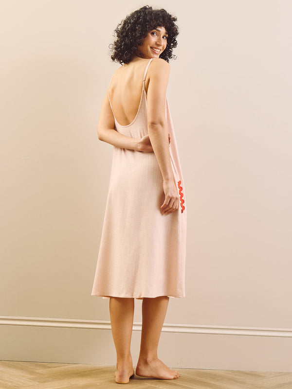 model wears pink nightie with red trim on a beige background, back