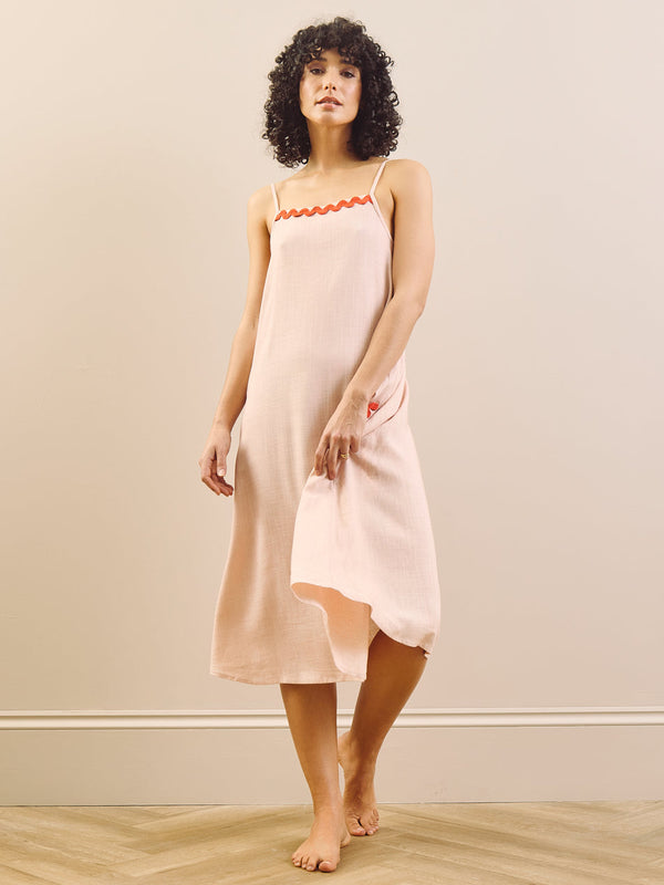 model wears pink nightie with red trim on a beige background