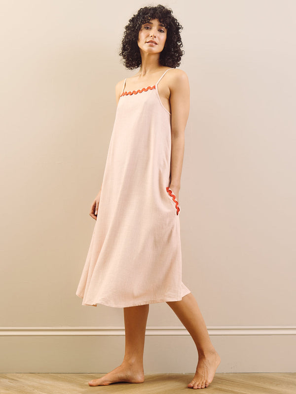model wears pink nightie with red trim on a beige background