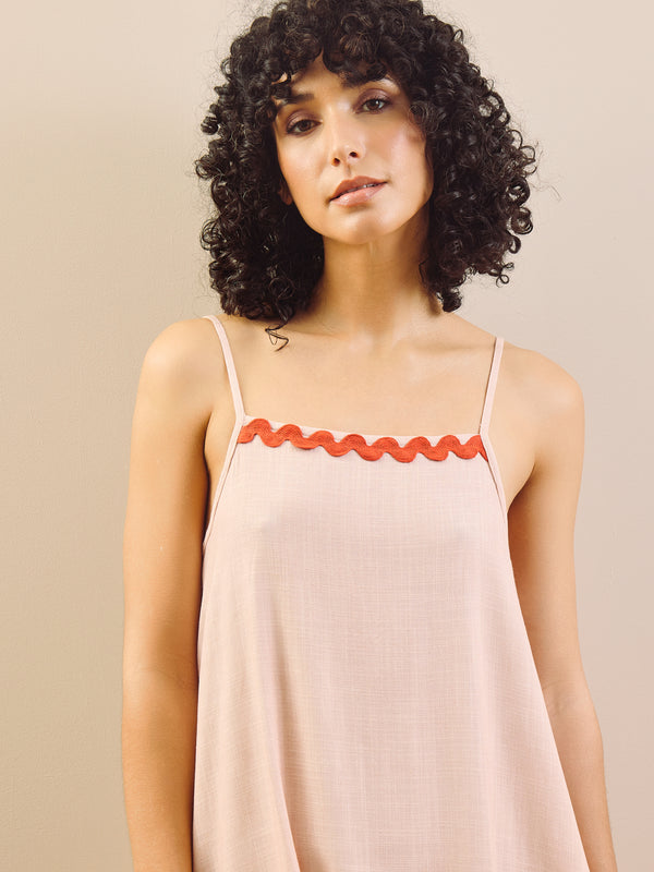 model wears pink nightie with red trim on a beige background, detail 