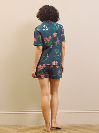 Woman wearing a navy floral short pyjama set against a plain background