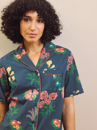 Woman wearing a navy floral short pyjama set against a plain background