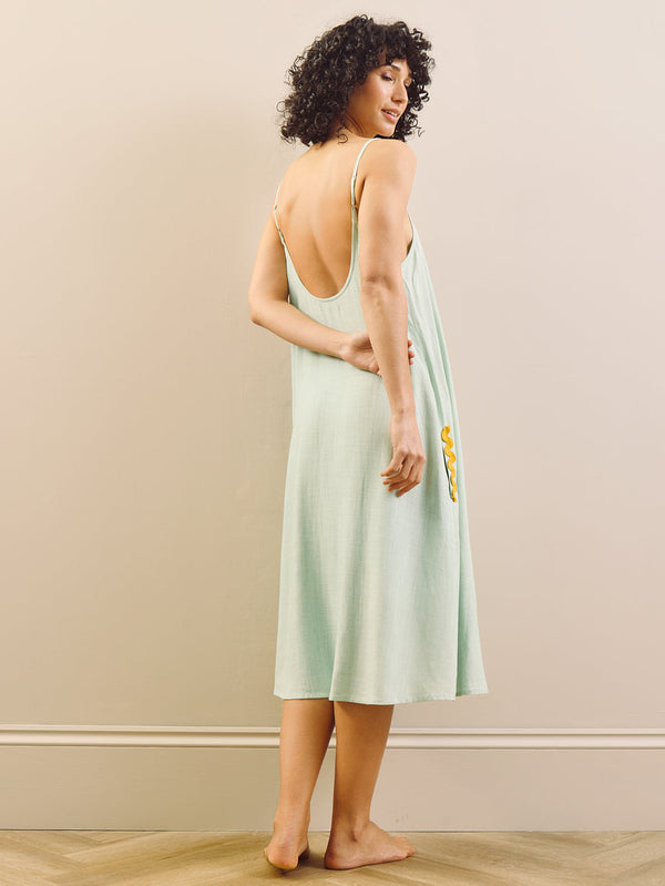 model wears linen blend nightie with contrast trim against a beige wall. Back detail