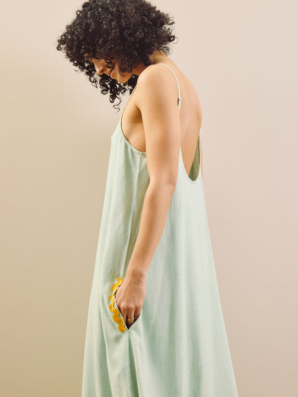model wears linen blend nightie with contrast trim against a beige wall. Side detail