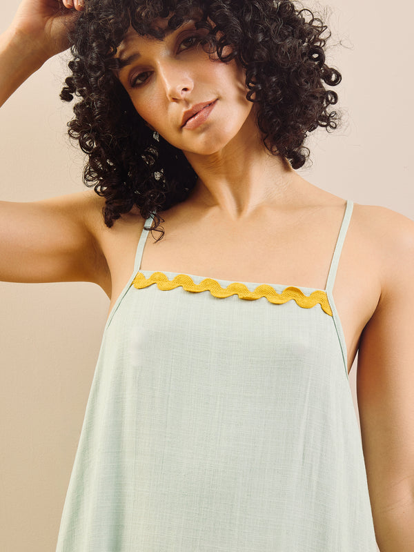 model wears linen blend nightie with contrast trim against a beige wall. 