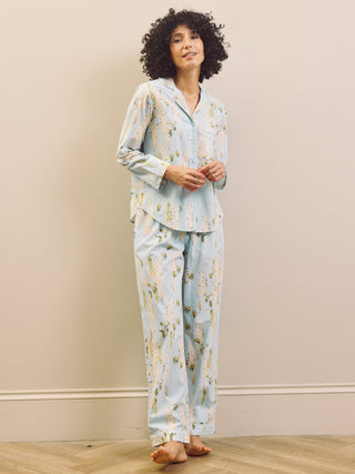 Woman wearing a light blue floral pyjama set against a beige wall.