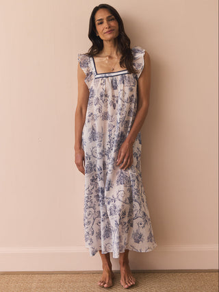 Model wears a navy and white toil print night dress against a beige wall. 