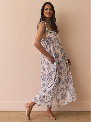 Model wears a navy and white toil print night dress against a beige wall. 