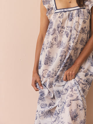 Model wears a navy and white toil print night dress against a beige wall. 