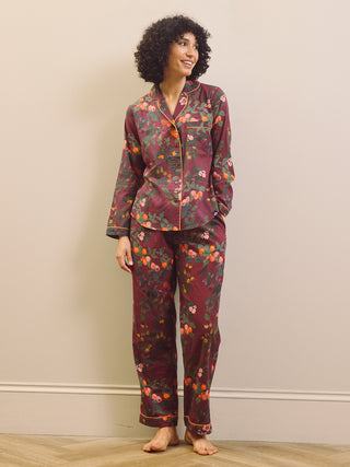 Woman wearing a burgundy floral pyjama set against a plain background