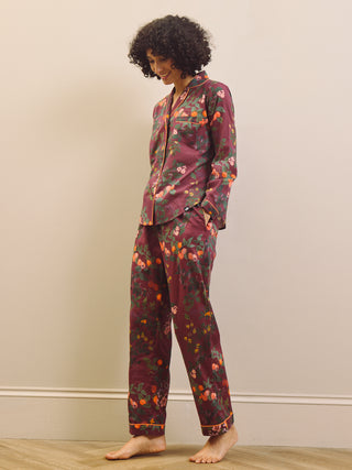Woman wearing a burgundy floral pyjama set against a plain background