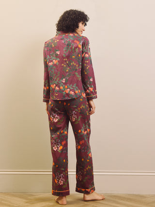 Woman wearing a burgundy floral pyjama set against a plain background