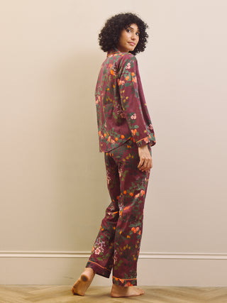 Woman wearing a burgundy floral pyjama set against a plain background