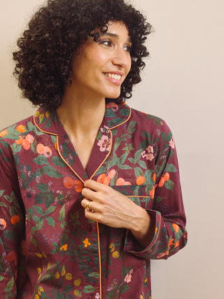 Woman wearing a burgundy floral pyjama set against a plain background