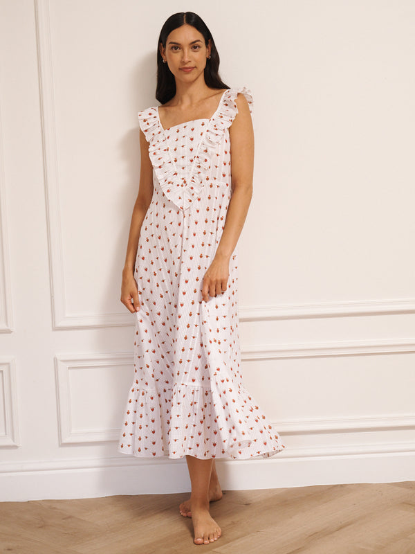 Model wearing white cotton seersucker nightdress with tiny sacred heart print, V-shaped frill neckline and midi-length hem, photographed against a neutral studio wall.
