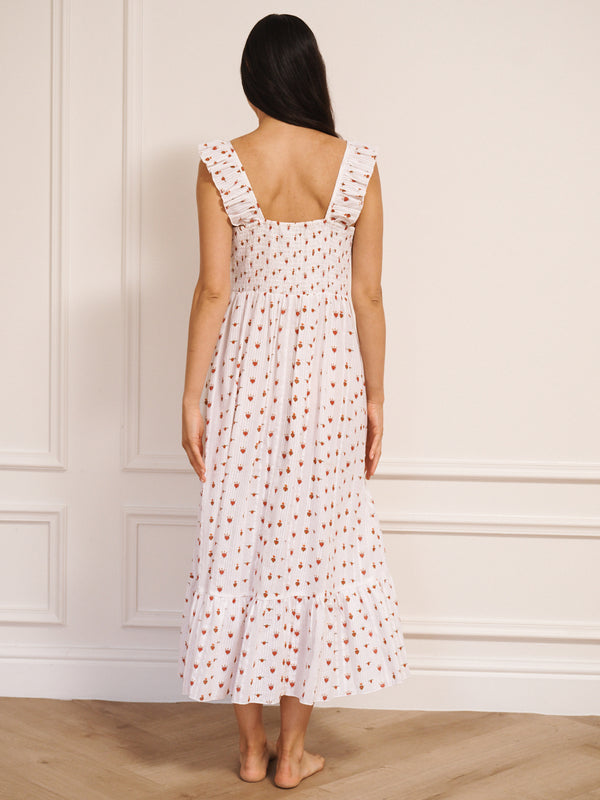 Model wearing white cotton seersucker nightdress with tiny sacred heart print, V-shaped frill neckline and midi-length hem, photographed against a neutral studio wall. Back detail