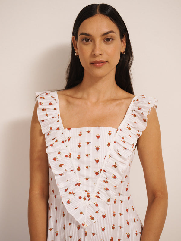 Model wearing white cotton seersucker nightdress with tiny sacred heart print, V-shaped frill neckline and midi-length hem, photographed against a neutral studio wall. detail