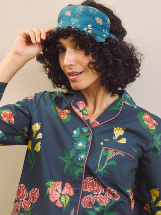 Woman wearing a floral pajama set with a matching eye mask against a neutral background